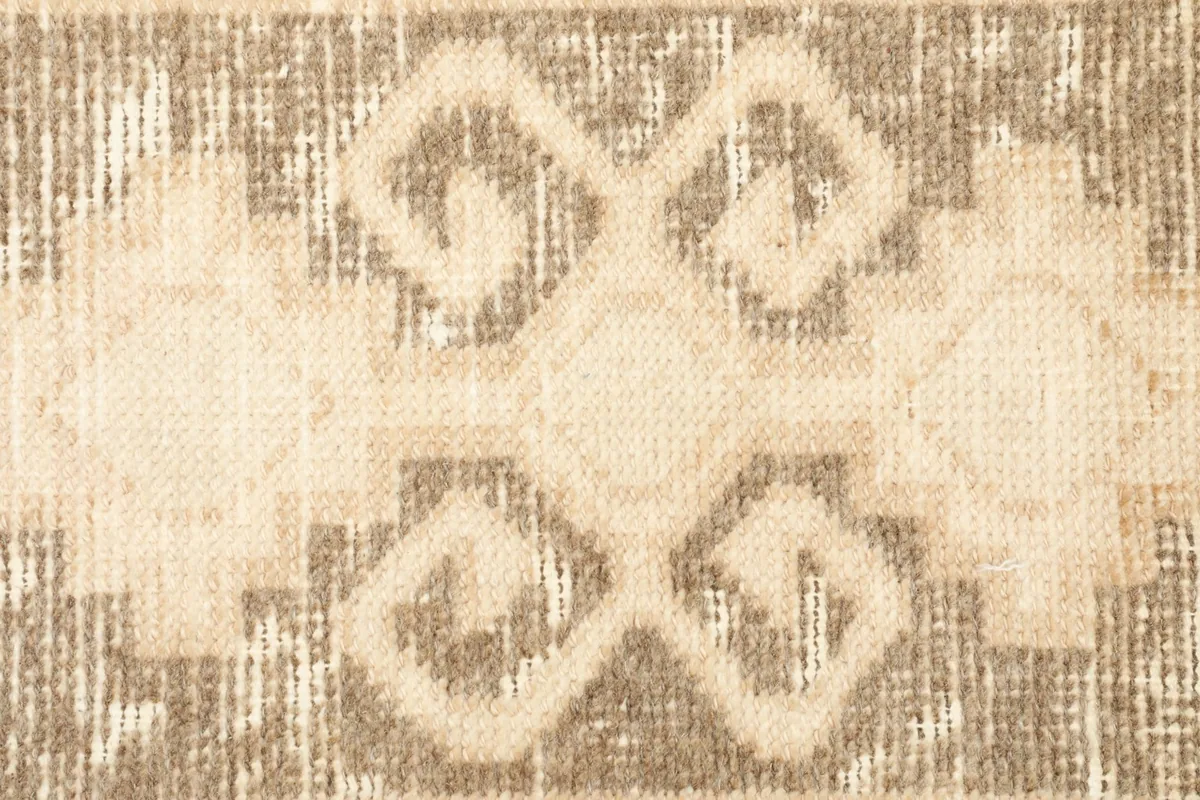 Macro detail of the distressed geometric pattern in brown and beige tones.