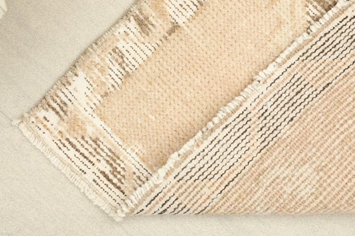 View of the rug's reverse side, showing the hand-knotted cotton foundation and wool knots.