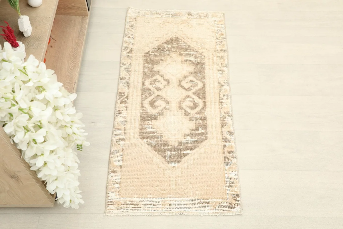 Close overhead view of the tan and brown geometric rug, showcasing its central medallion design.