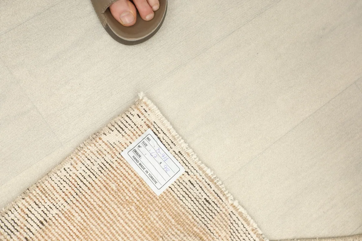 A foot next to the rug's corner, showing the scale and the label on the back.