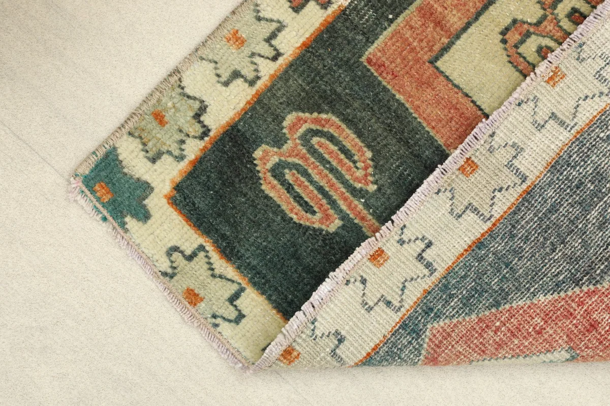 Folded corner of the rug, revealing the low wool pile and the hand-knotted cotton foundation