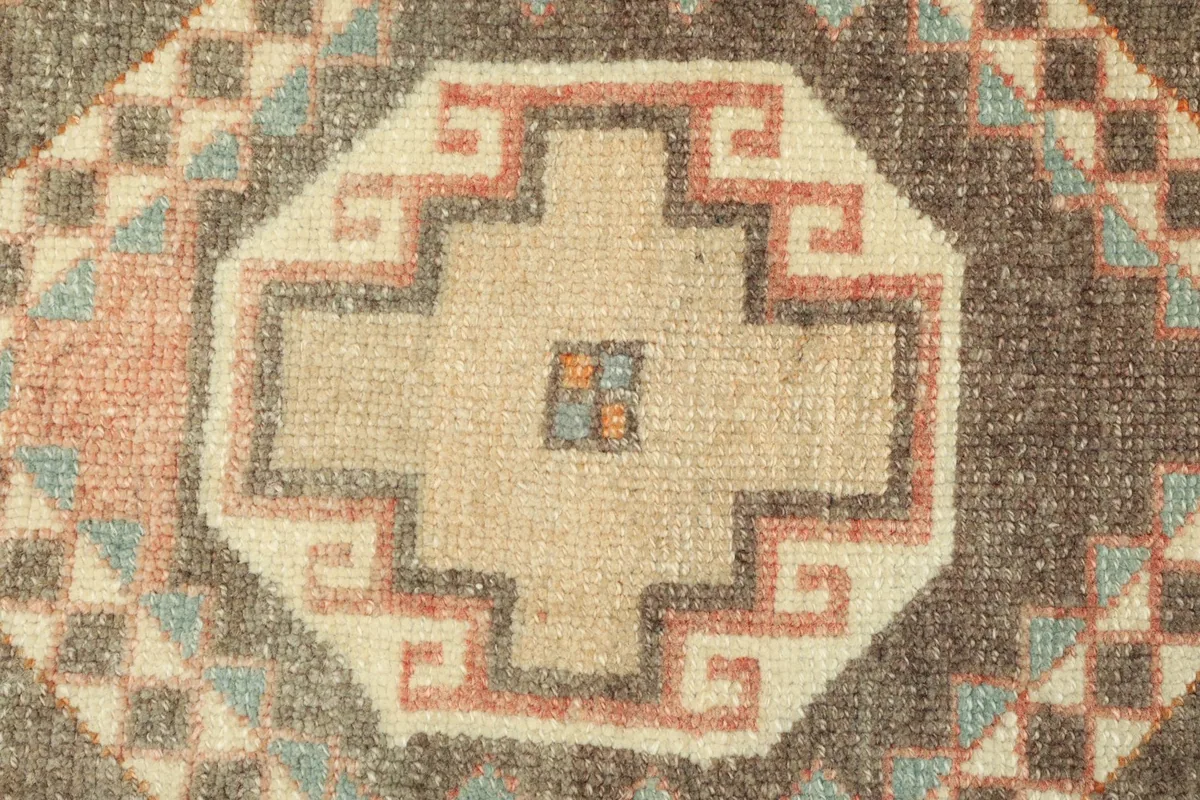 Detailed view of a central beige geometric medallion with a red and blue outline on the charcoal background