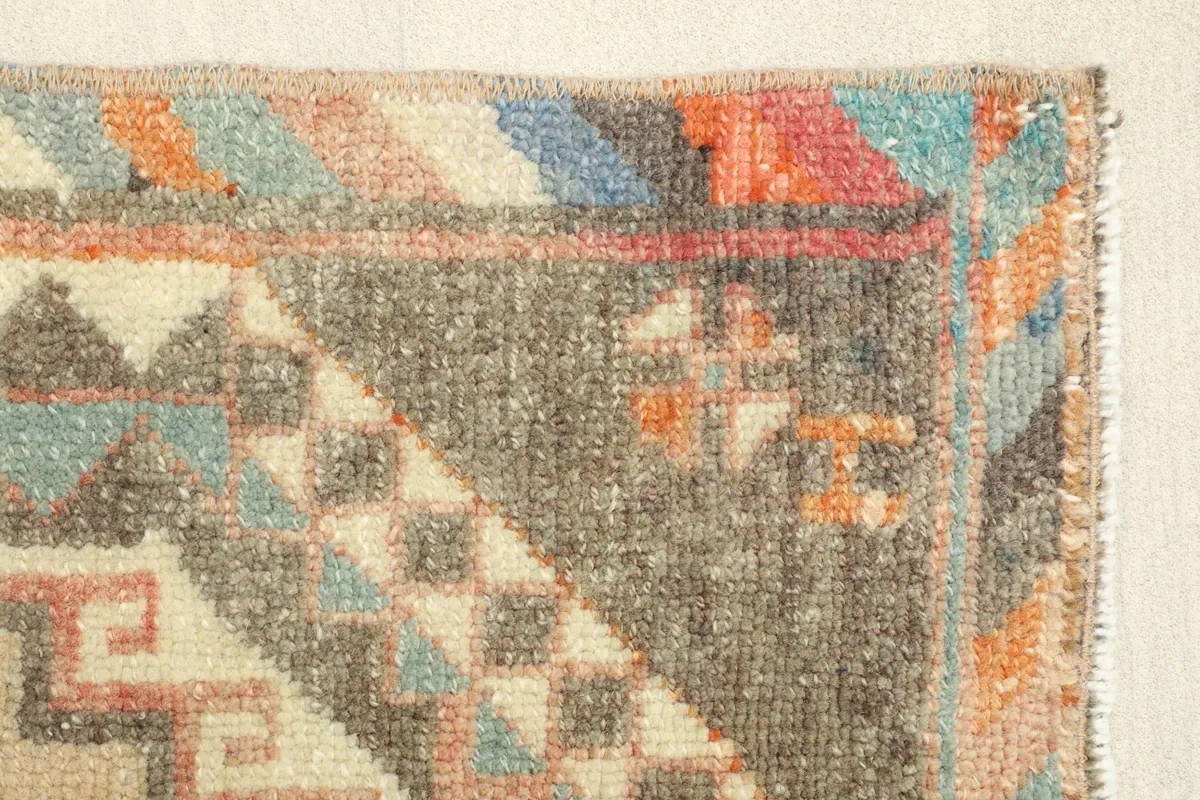 Close-up of the rug's border, highlighting the blue, orange, and red tribal patterns and low pile