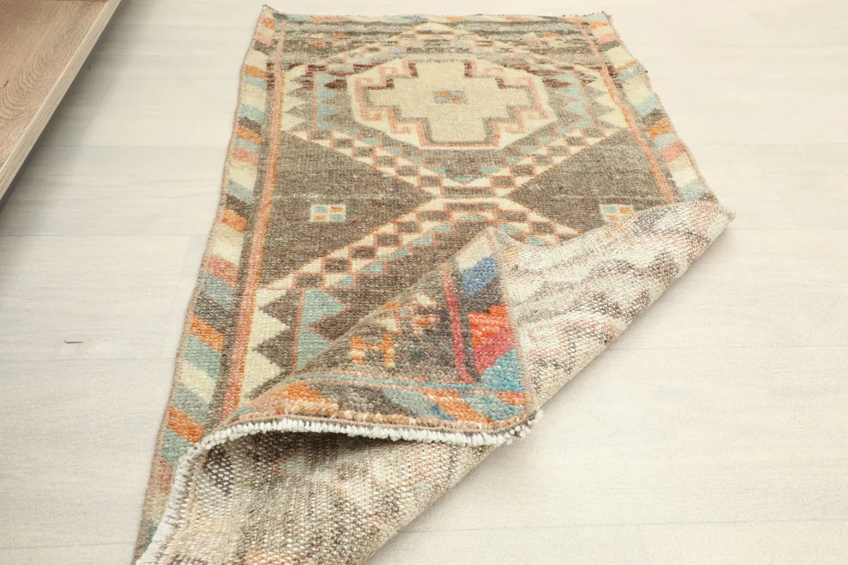 Partial view of the rug with one end folded back, showing the back and front textures