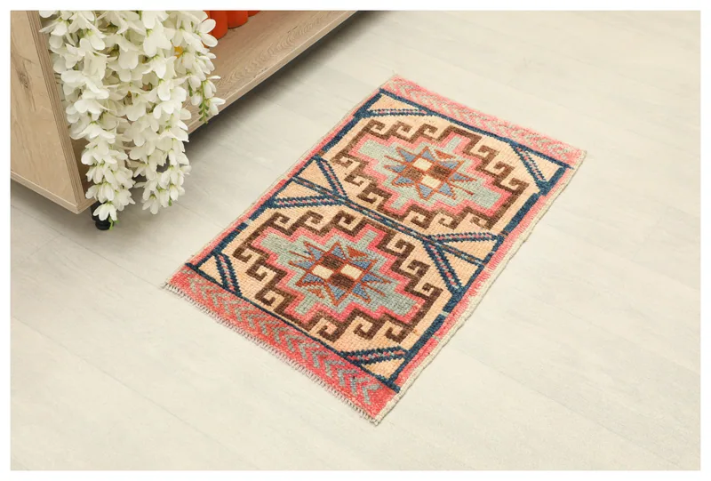 Full top view of the 1'5" x 2'4" beige, rose, and navy geometric Anatolian rug on a white background.