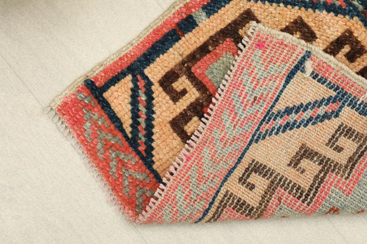 Rug partially folded to display the thickness of the hand-knotted wool pile and the reverse side.