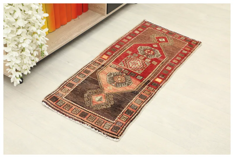 Full top view of the vintage brown and red Anatolian rug on a light floor.