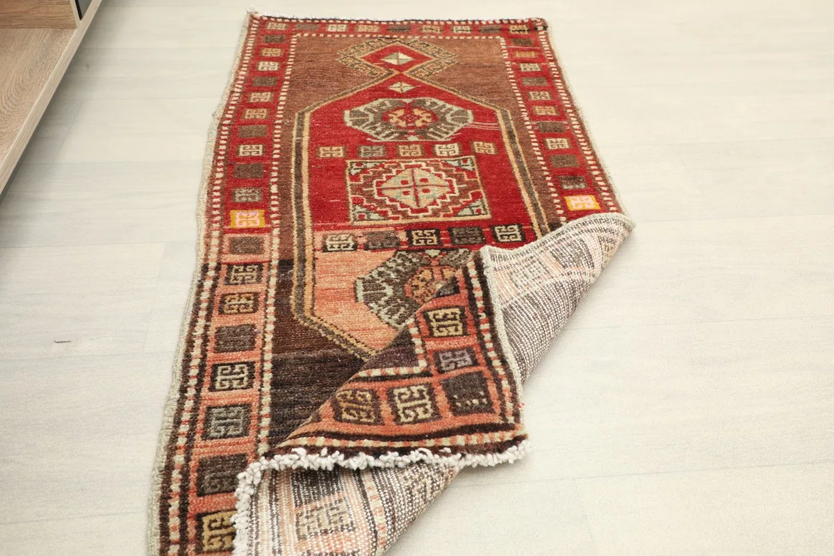 Rug partially folded, showing the flexibility and texture of the vintage wool pile.