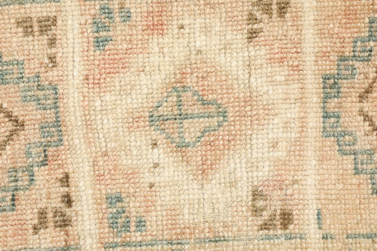 Detailed view of the hand-knotted pile and a central geometric design in blue and rose.