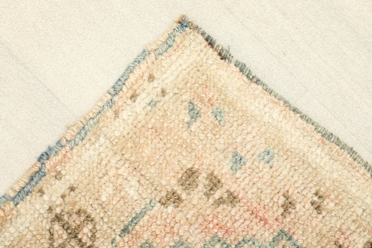 Close-up of a corner, showing the subtle blue edge finishing and texture of the wool pile.