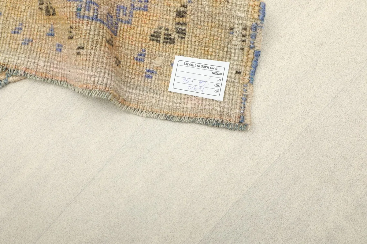 Close-up of the rug's back, showing the hand-knotted cotton foundation and a product label.