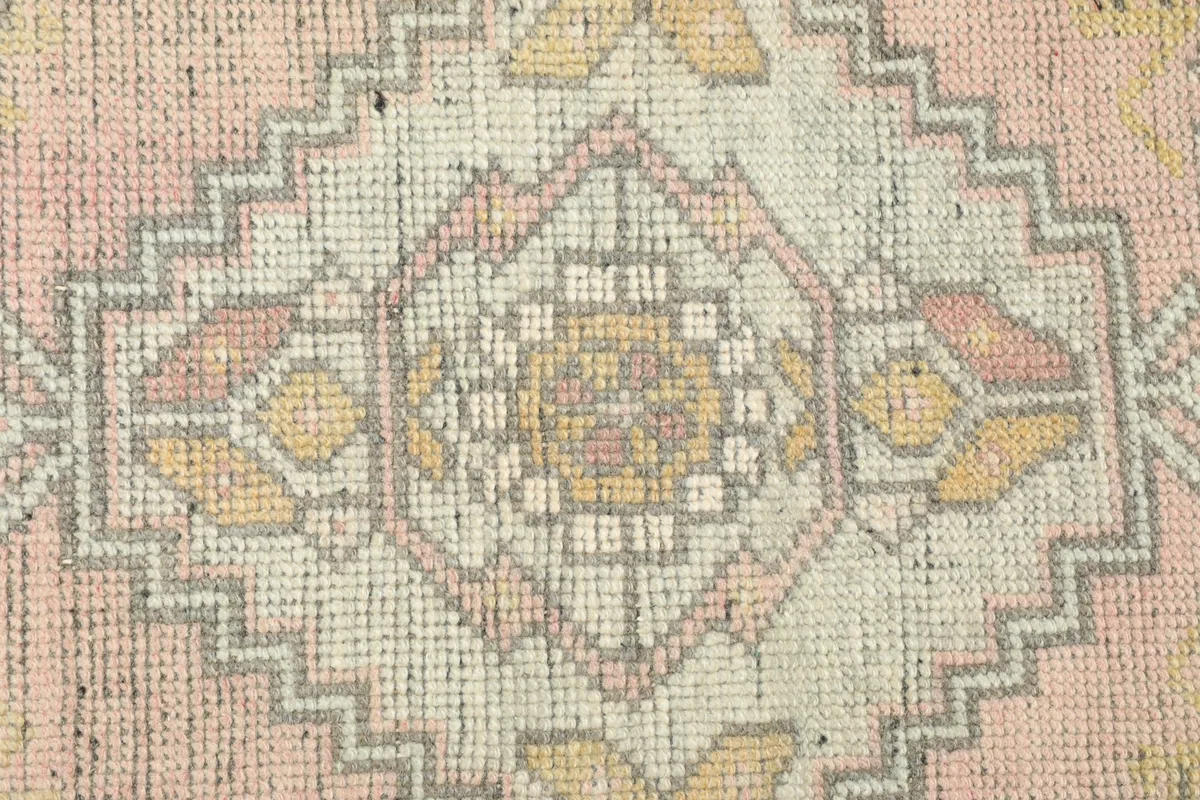 Close-up detail of the central geometric medallion with gold, ivory, and rose tones.