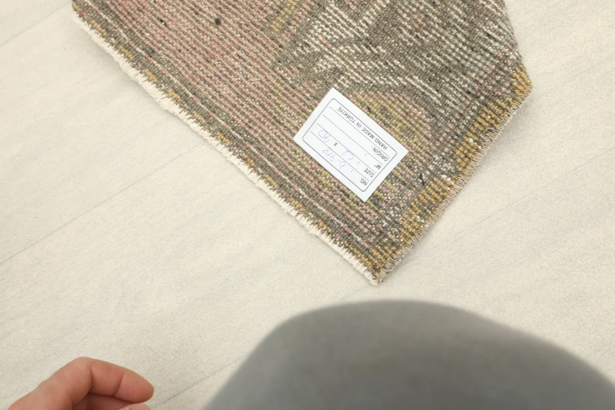 View of the back of the rug, showing the hand-knotted cotton foundation and a product label.