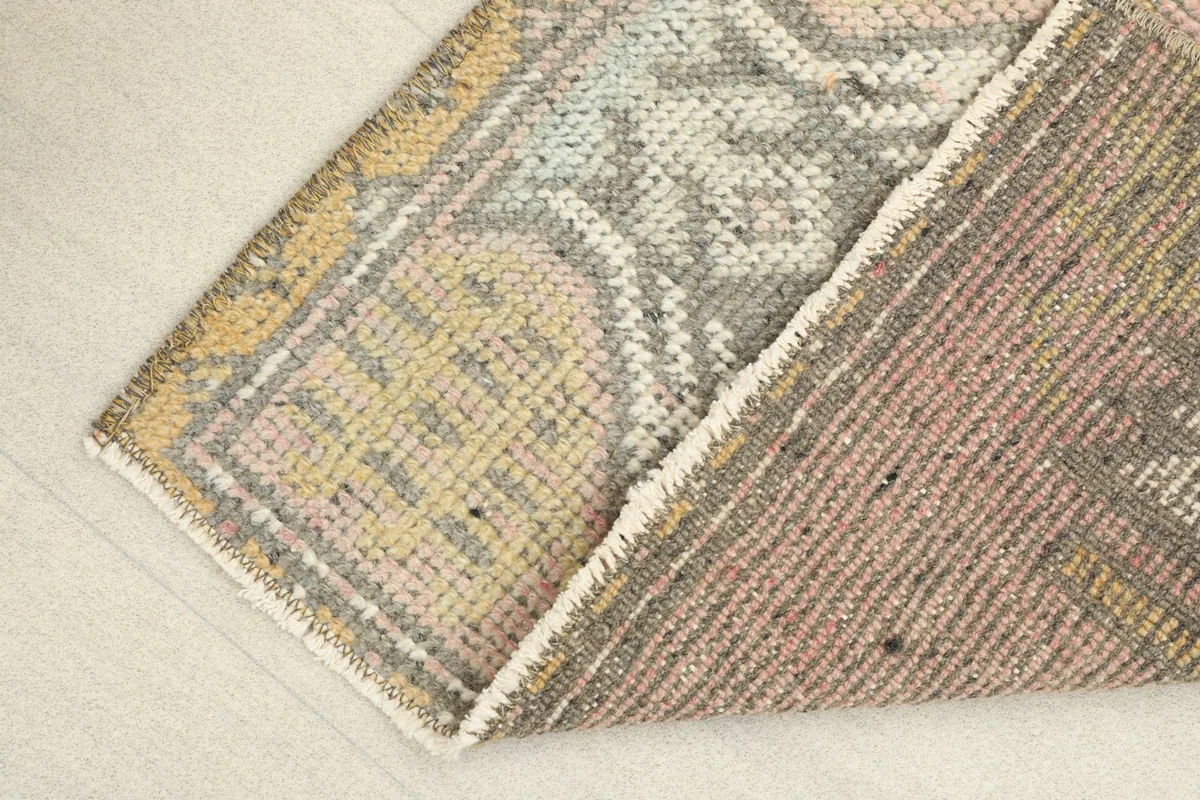 View of the rug partially folded, showing the wool pile on cotton foundation.