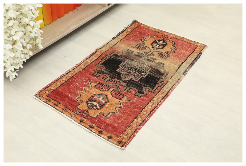 Full top view of the vintage red and orange geometric doormat on a white background.