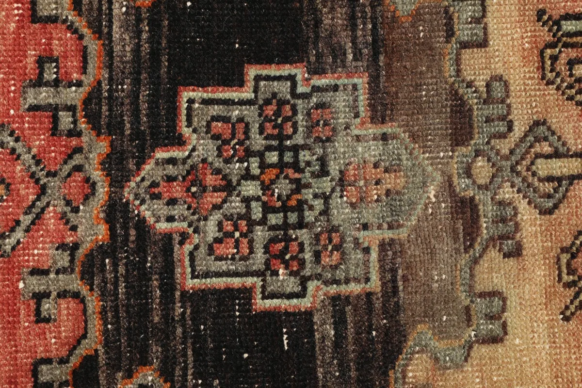 Detailed view of the intricate geometric patterns and faded colors in the rug's central design.