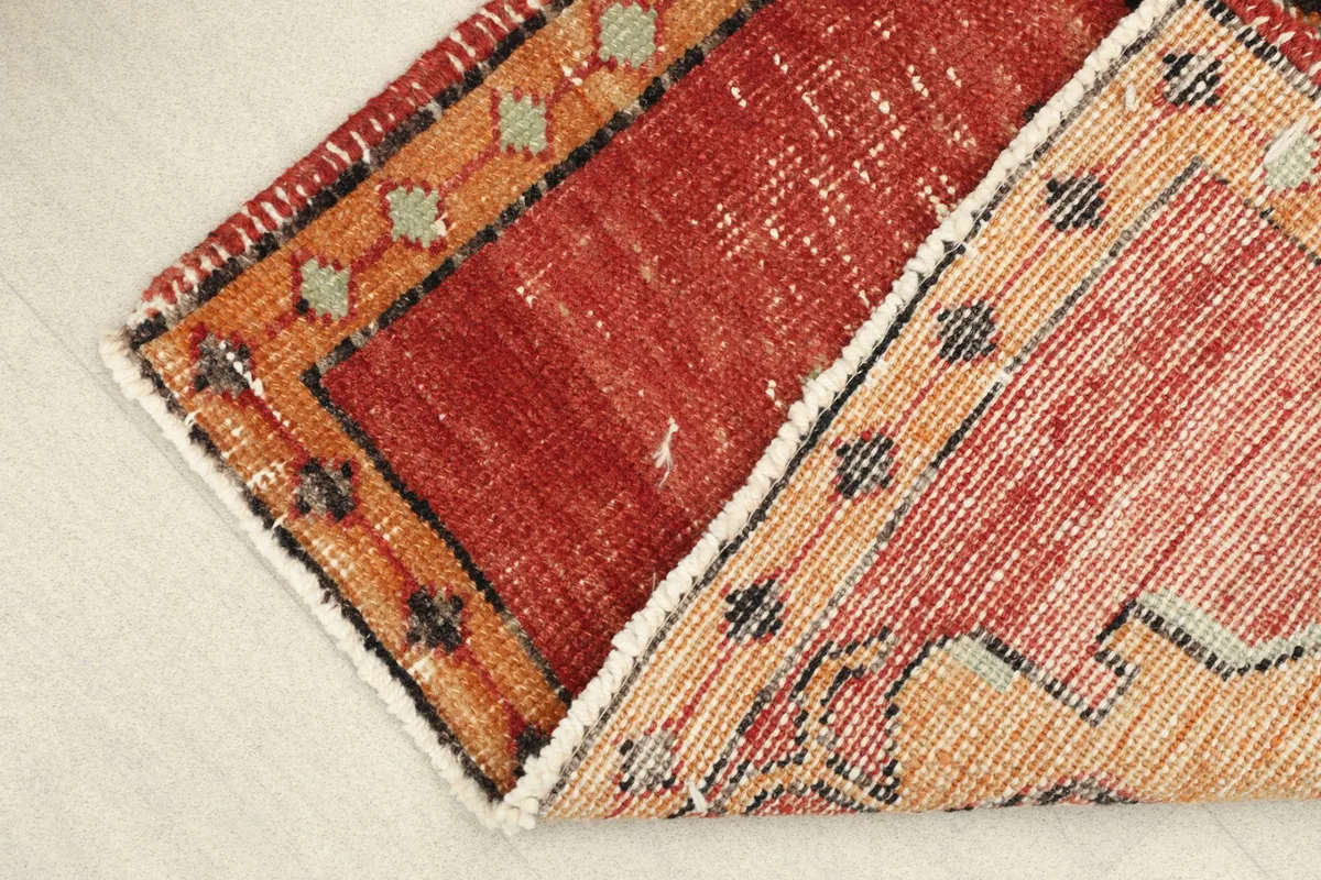 Folded corner revealing the wool pile texture on the front and the cotton foundation on the back.