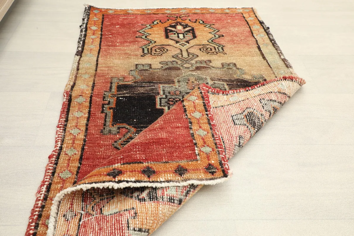Rug partially folded, showing the flexibility and construction of the hand-knotted vintage piece.
