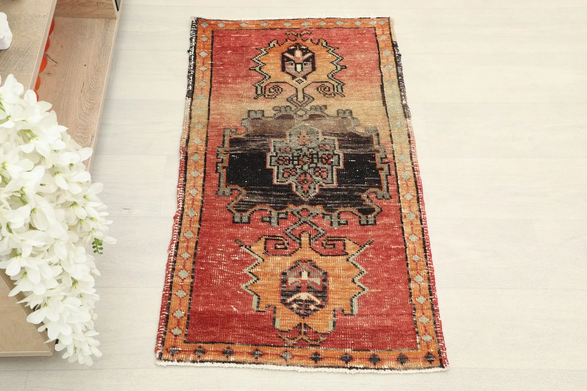 Overhead view showcasing the full red and orange vintage rug with its central black geometric design.