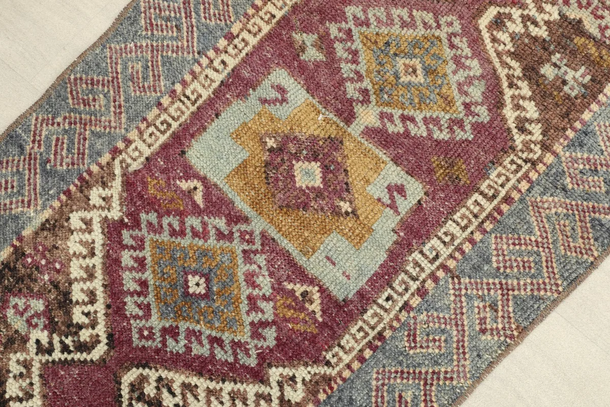 Close-up view of the central geometric motifs in rose, gold, and blue, showing the texture and colors.