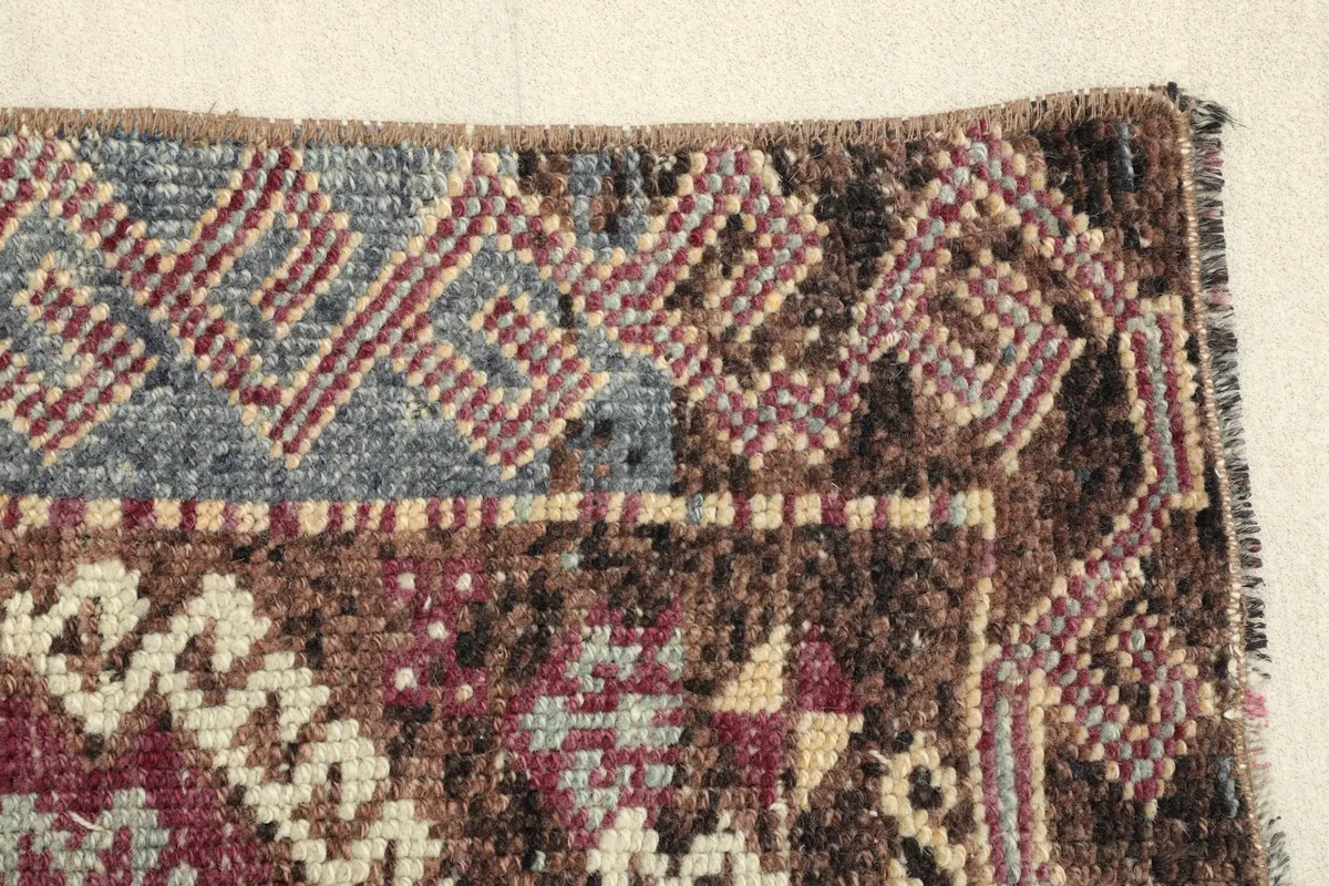 Close-up of the rug's border, showcasing the distinct blue and brown tribal patterns.