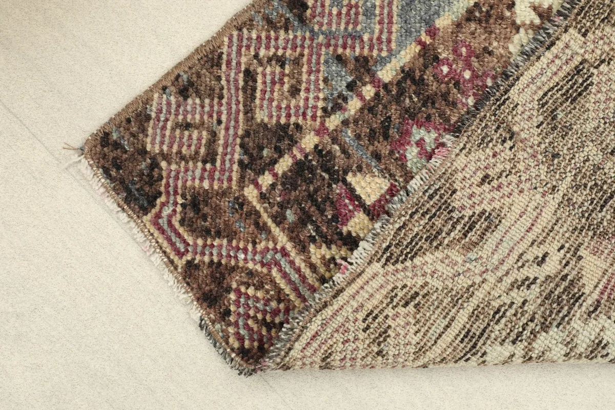 View of the back of the rug, revealing the tightly hand-knotted cotton foundation and wool pile.