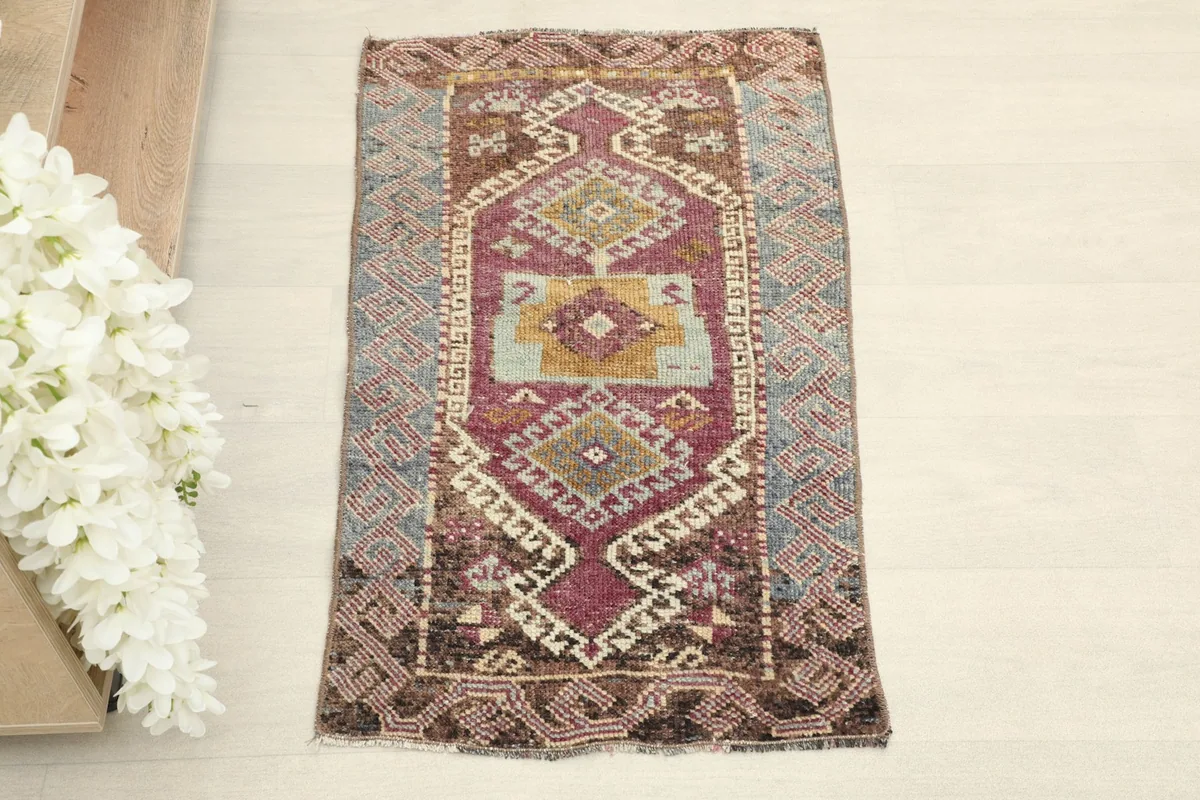 Direct overhead shot of the hand-knotted mini area rug, highlighting its rose field and blue-brown border.