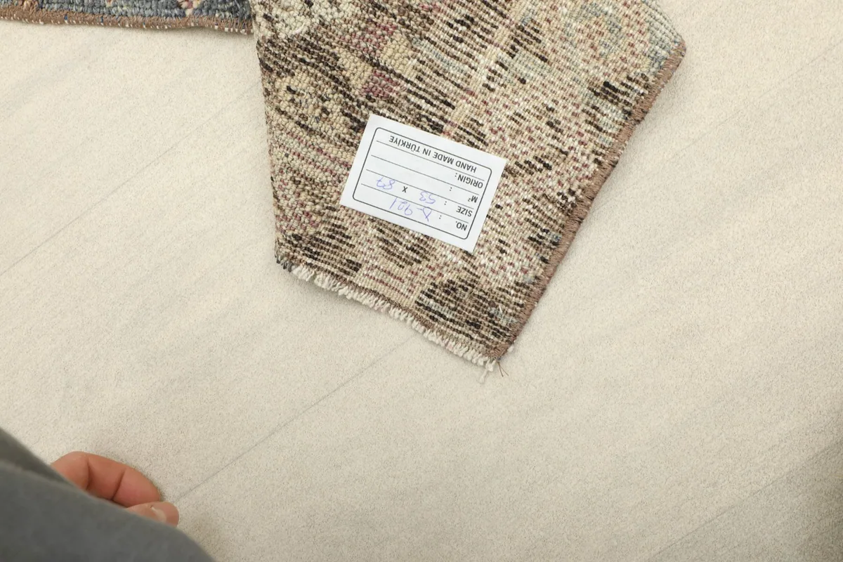 Label attached to the rug, displaying product details and origin, with a hand visible for scale.