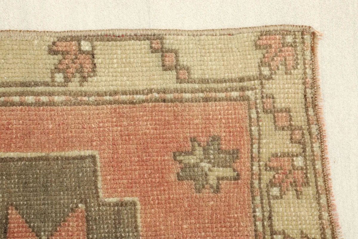Close-up of the beige border pattern and the transition to the rust field, showing minor wear.