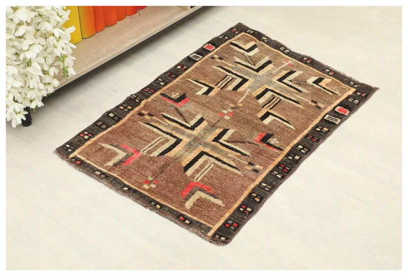 Top view of a 1'10" x 2'10" brown geometric tribal rug on a white background.