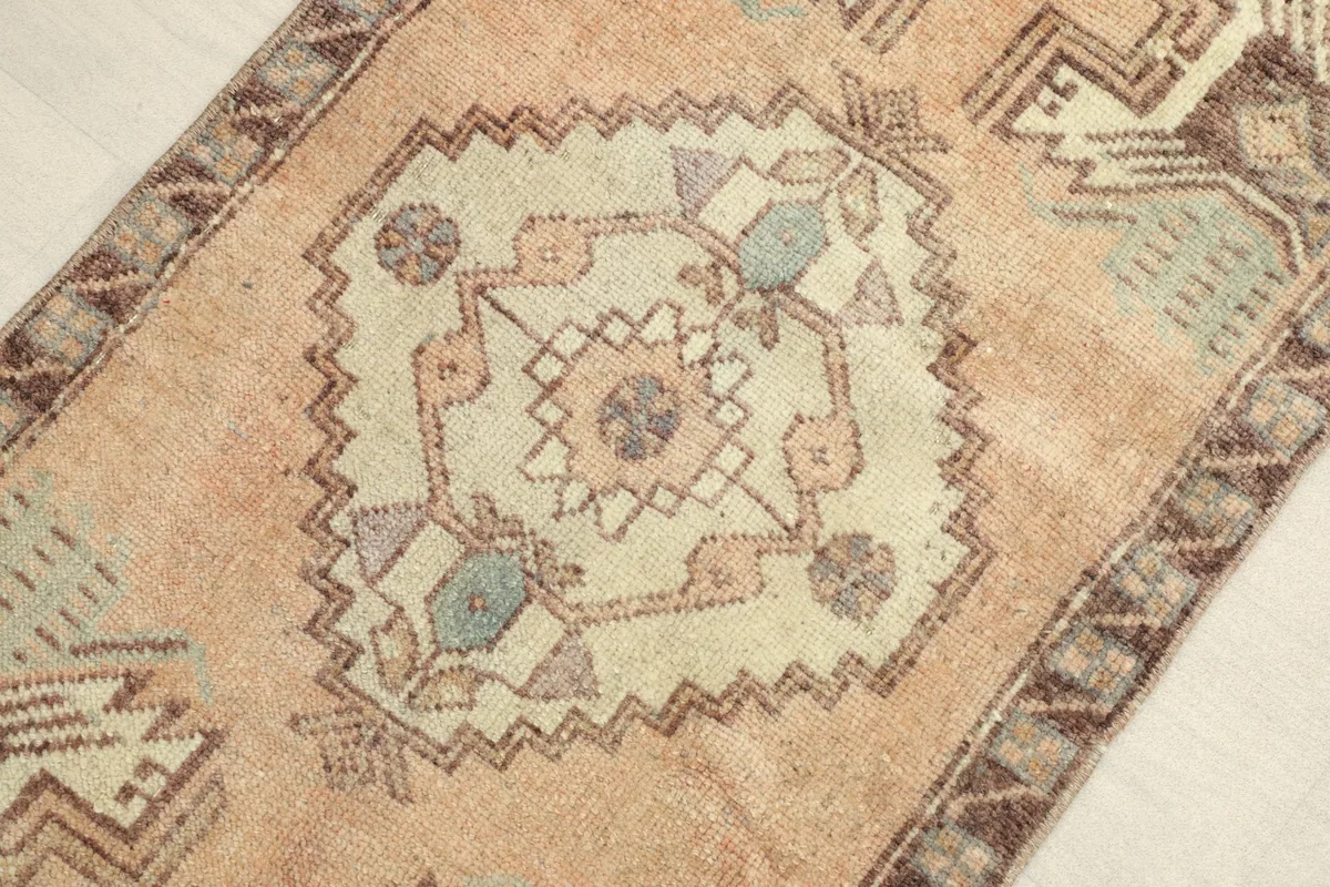 Close-up of the central geometric medallion with olive, rose, and beige details in the rug.