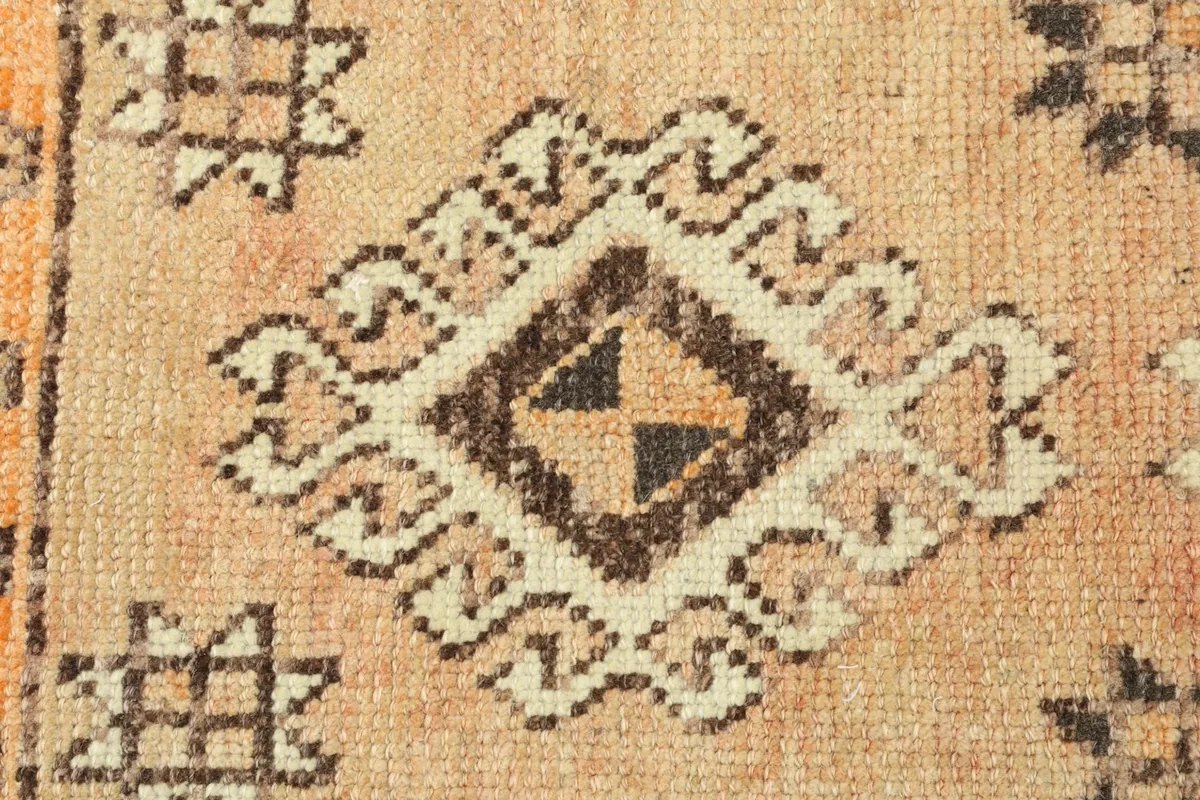 Close-up detail of a central geometric medallion-like motif in brown and beige tones.