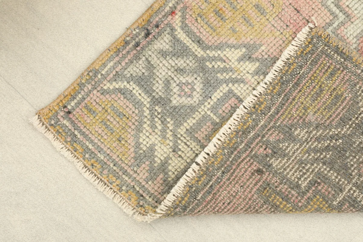 View of the rug's underside and folded edge, showing the cotton foundation and knotting.