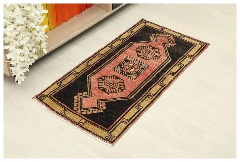 Full top view of the 1'8" x 3'5" rose and black vintage Anatolian doormat rug on a white background.