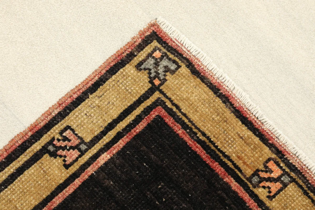 Corner detail showing the tan outer border with small tribal symbols and the black inner border.