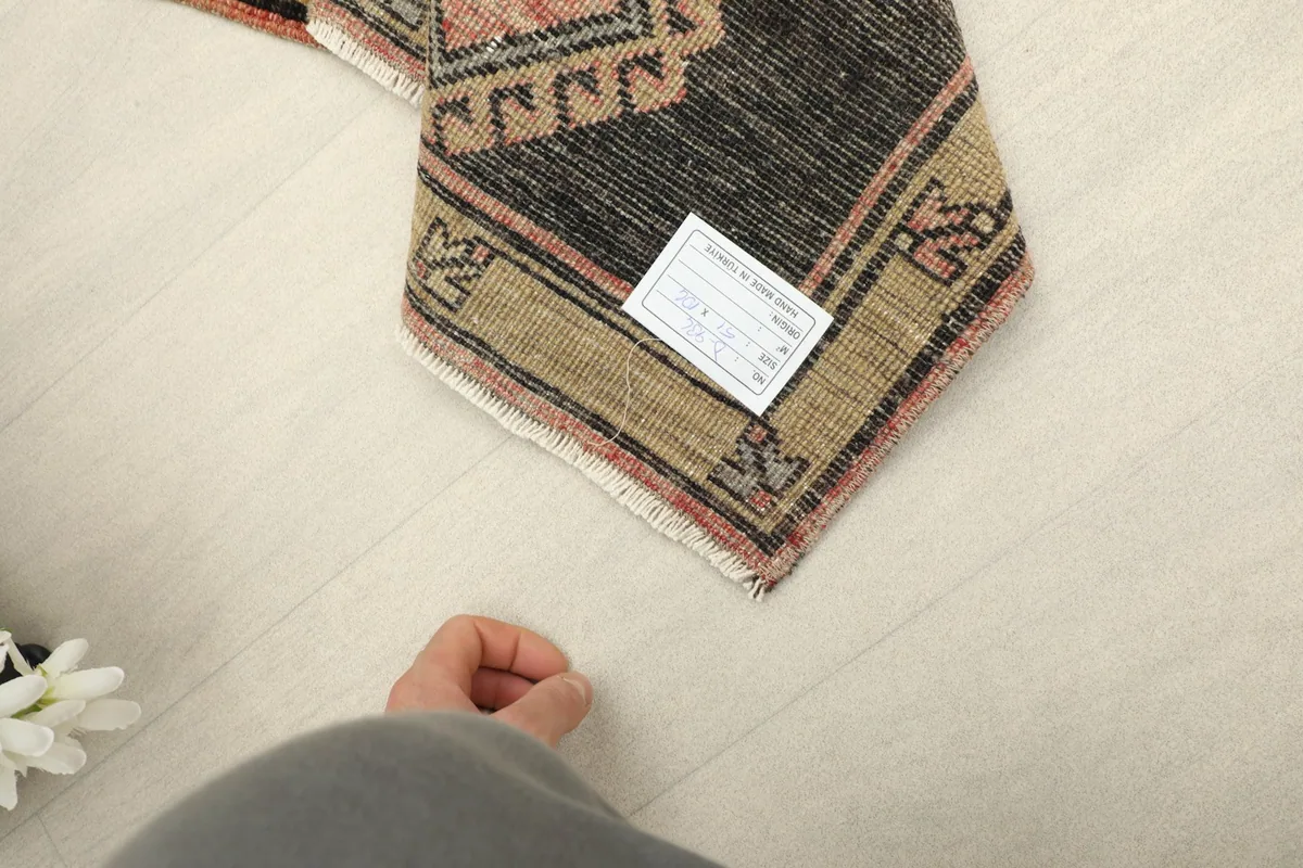 A hand pointing to the back of the rug, showing the authentic hand-knotted craftsmanship and label.