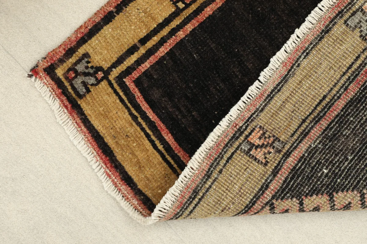 View of the rug folded to show the wool pile texture and cotton foundation on the underside.