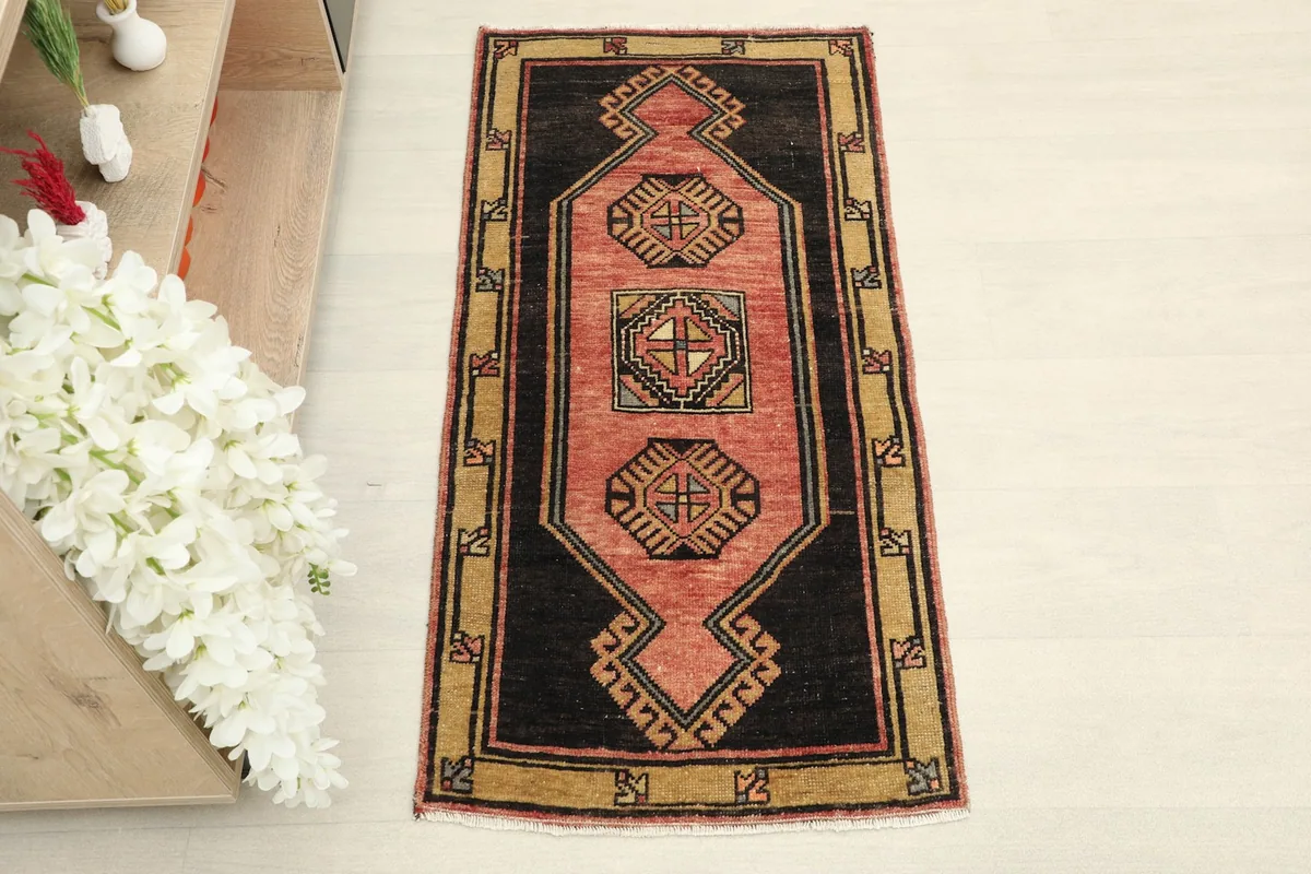 Overhead view of the hand-knotted vintage rug, showing its rose field and black and tan border.
