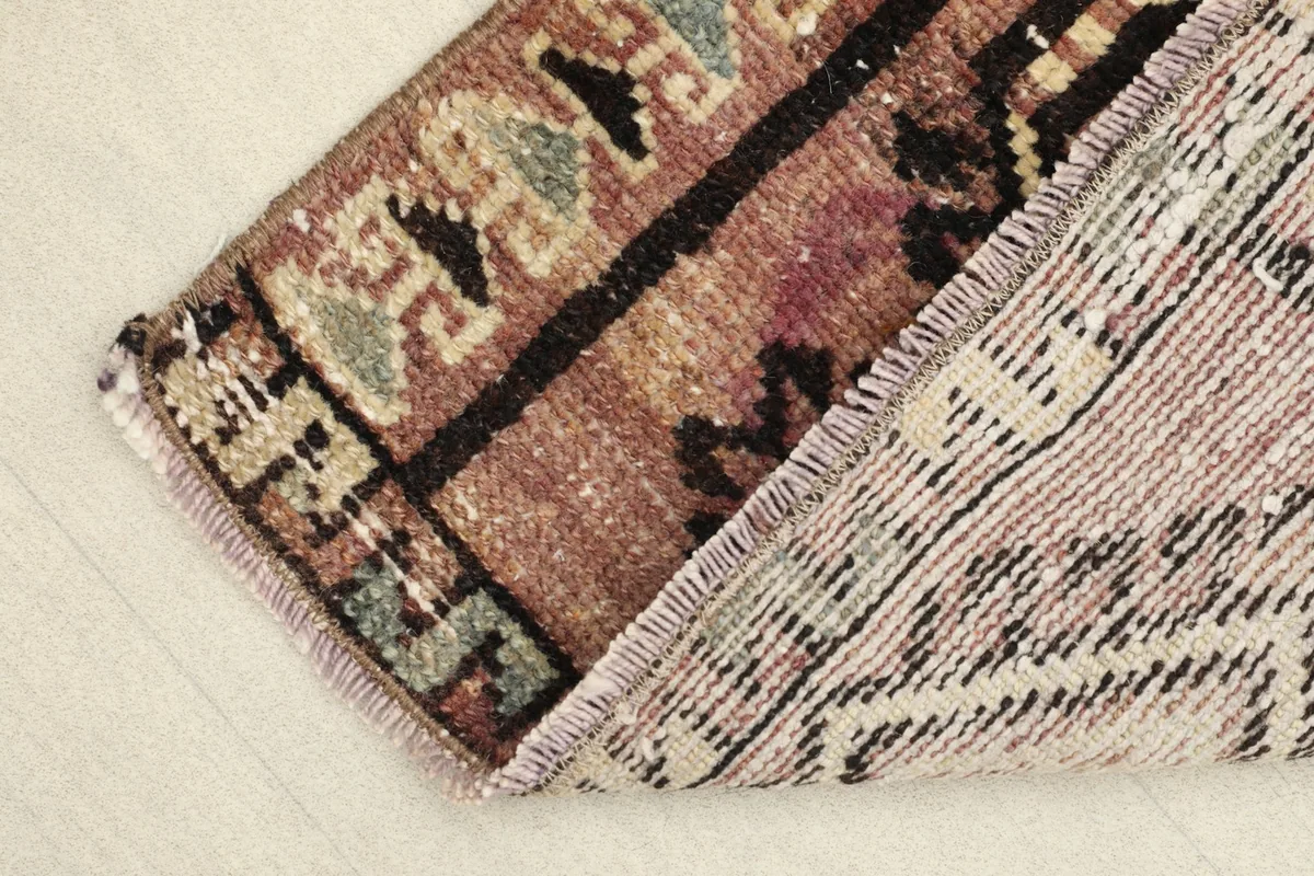 Corner of the rug folded back to show the wool pile and cotton foundation