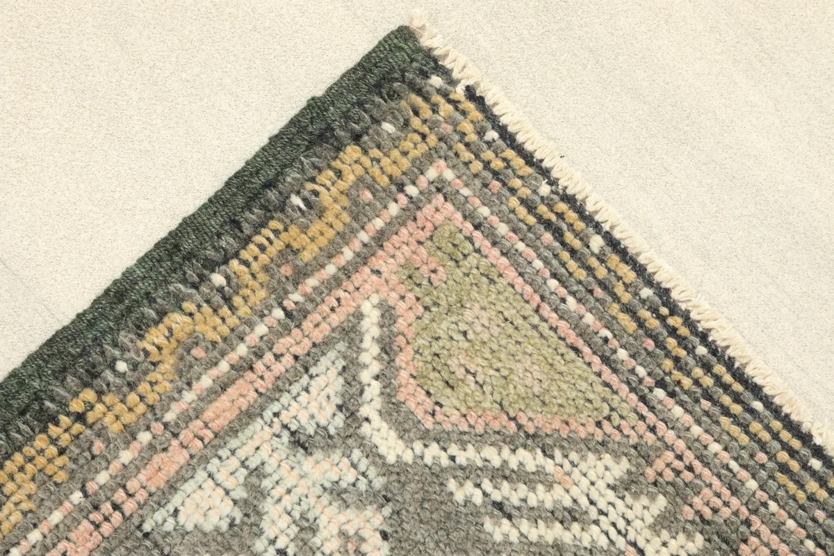 Corner detail of the rug, showing the black border and accent colors of gold and rose.