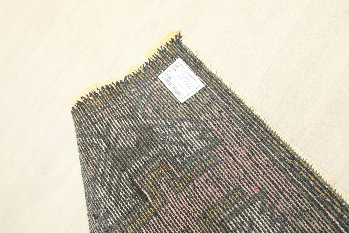 View of the back of the vintage rug, showing the tightly woven cotton foundation and wool knots.