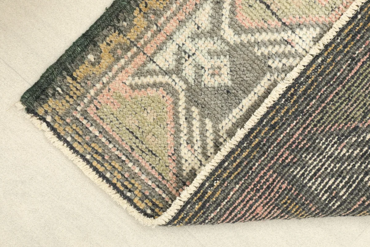 Corner of the rug folded back to show the cotton foundation and density of the hand-knotted wool.