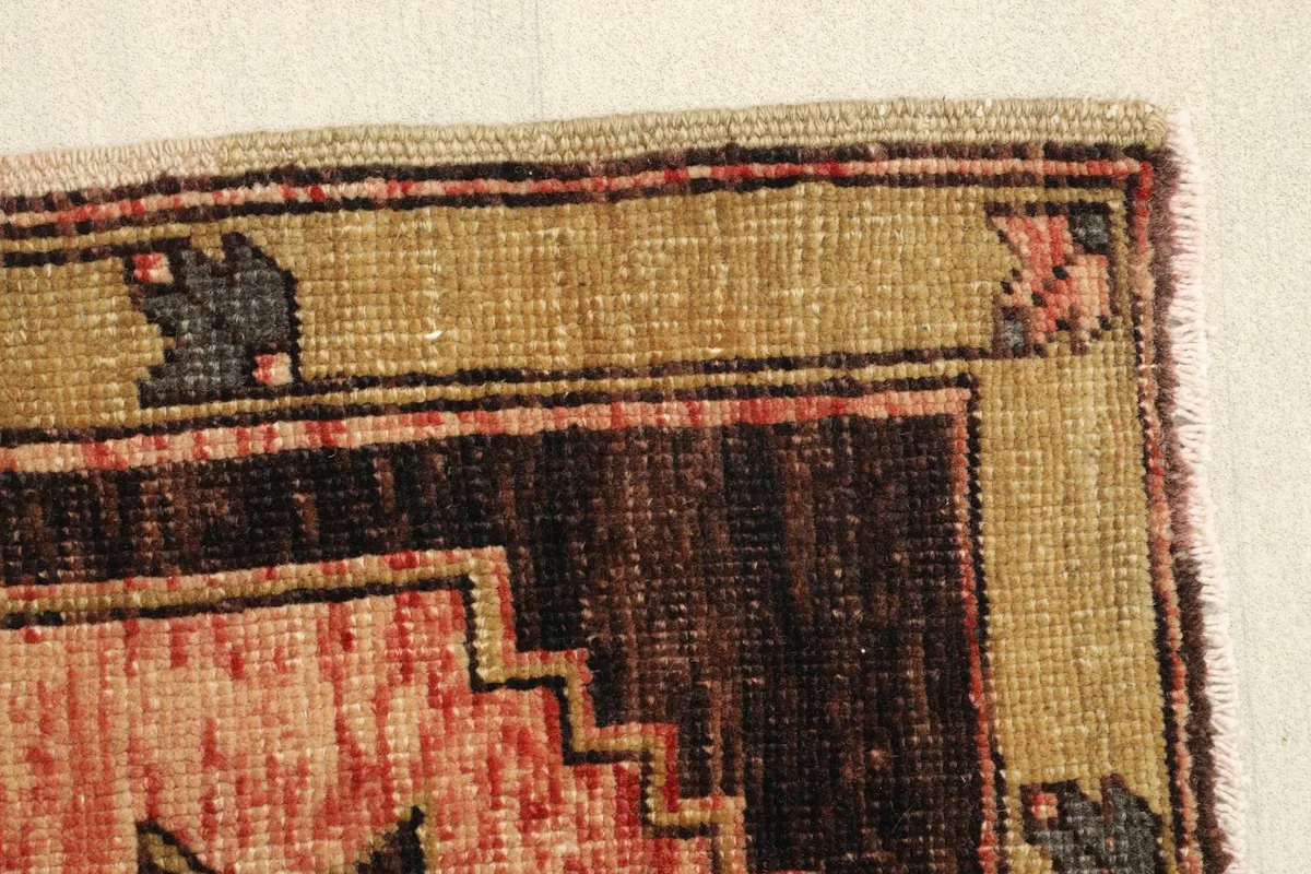 Close-up of the rug's edge, highlighting the tan border and the rich, dark brown section.