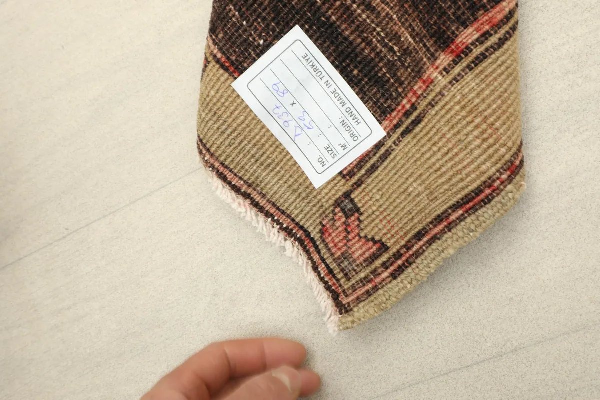 View of the rug's back, revealing the hand-knotted construction and a product label.