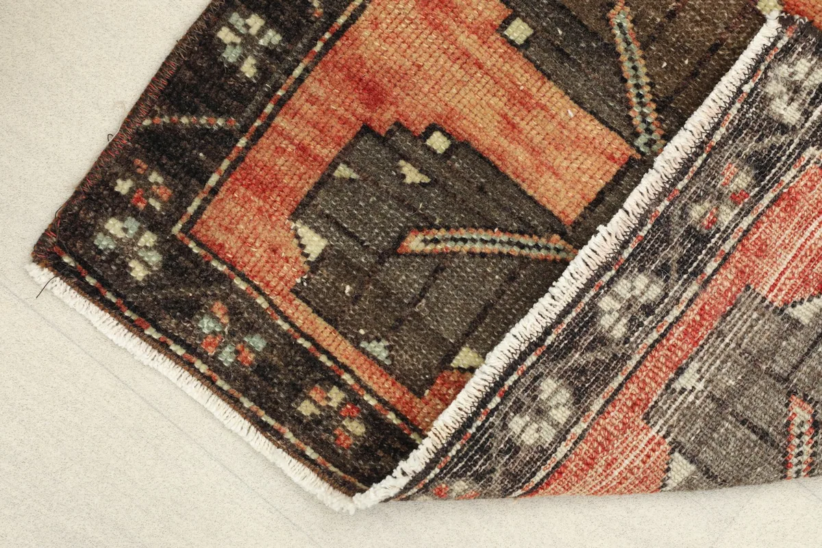 View of the rug's low pile and fringe, with a corner folded over to show the backing.