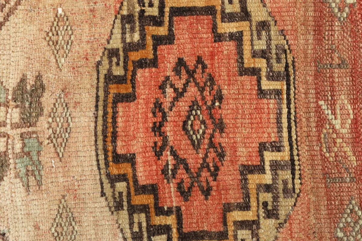 Close-up detail of the central rust-colored geometric medallion with black and beige outlines.