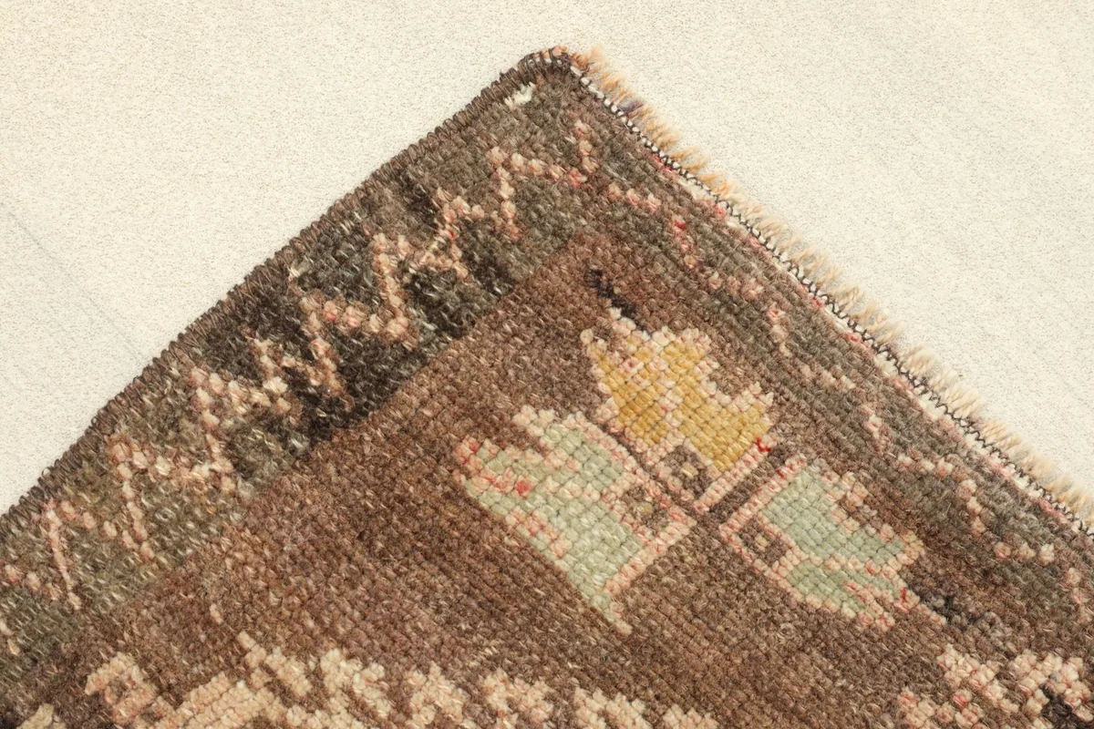 Close-up of a corner, showing the brown border and accents of green and yellow in the motifs.