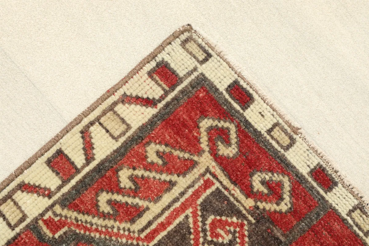 Corner detail showing the ivory and brown geometric border of the vintage Anatolian rug