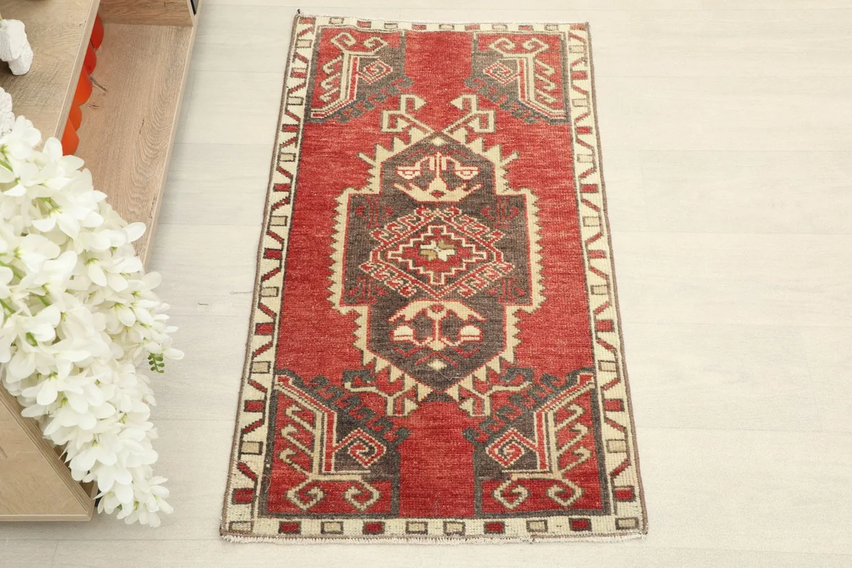 Overhead view showcasing the red field, brown medallion, and ivory geometric patterns of the rug