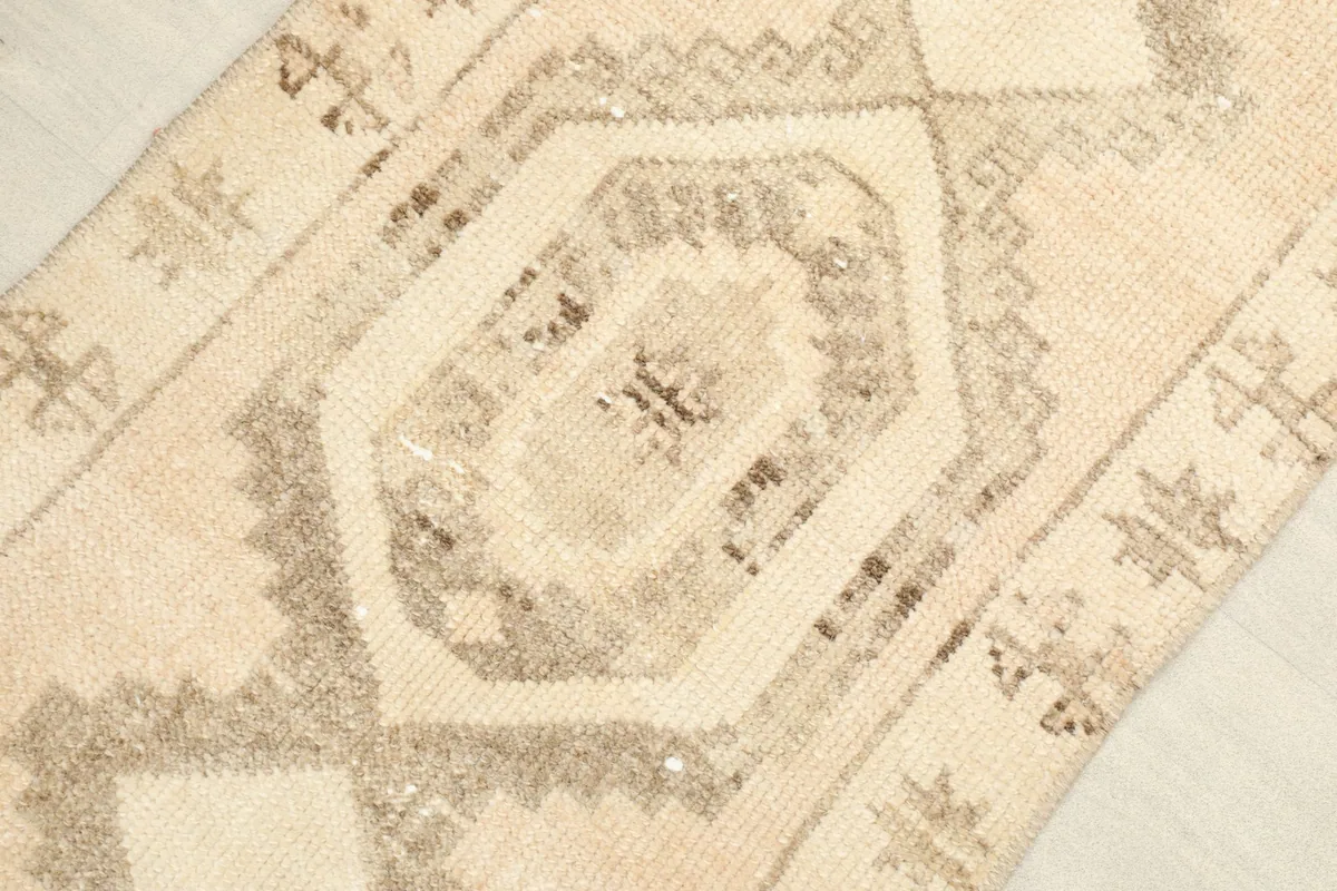 Angled close-up view of the central geometric medallion and surrounding tribal motifs in beige and brown.